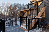 Modern Patio Interior with staircase in wooden covered in snow black stairway hand rail next to chopped firewoods