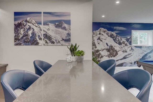 a long table with four seats in a newly renovated basement with pictures of mountains on the wall behind