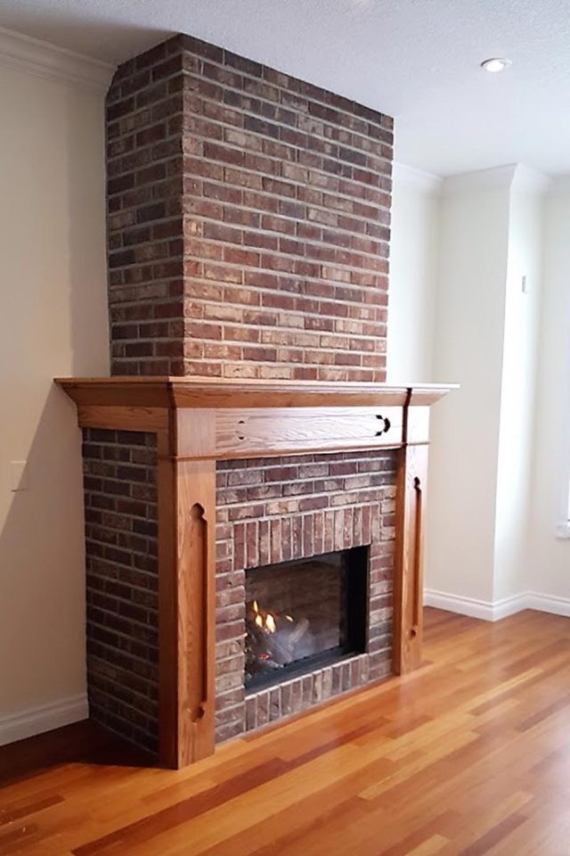 bare brick fireplace with wood paneling