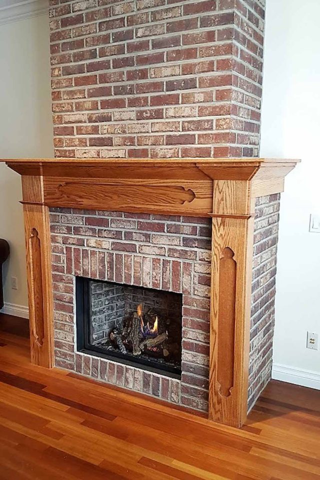 bare brick fireplace with wood paneling